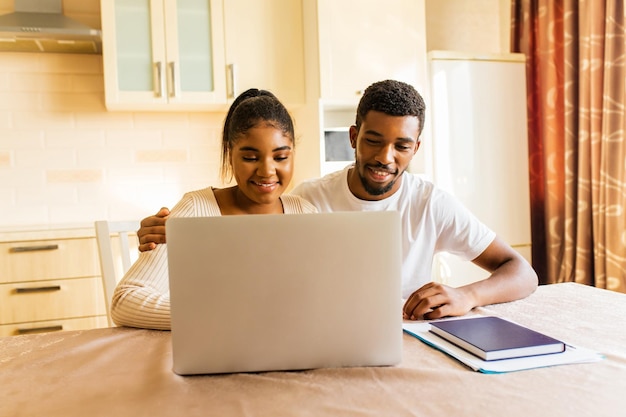 Couple afro-américain gérant la banque des finances et utilisant un ordinateur portable dans la cuisine