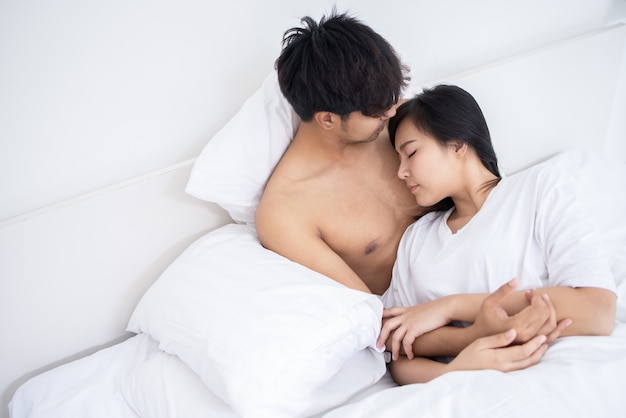 Photo couple asiatique homme et femme sur le lit dans la chambre blanche