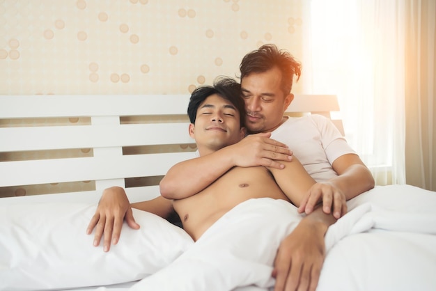 Photo un couple gay amoureux allongé sur le lit à la maison.