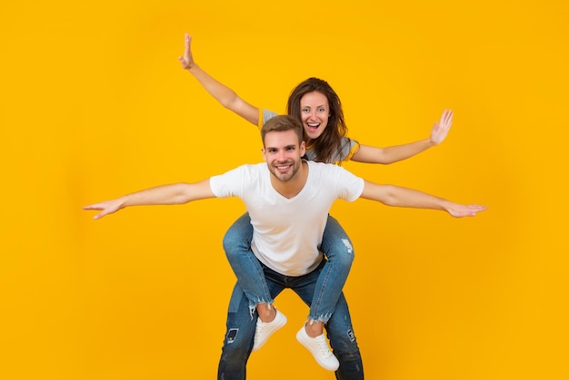 Un couple heureux amoureux d'une fille et d'un homme fait semblant de voler en faisant un tour de ferroutage sur fond jaune, ludique.