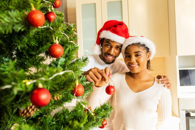 Couple hispanique latin décorant un sapin de noël avec une boule rouge à la maison