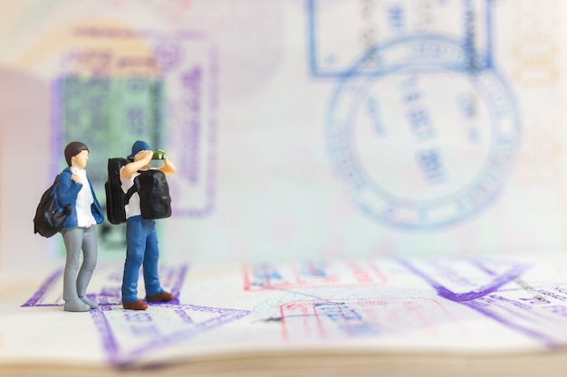 Photo couple de personnes miniatures debout sur un passeport avec estampillé d'immigration, travel concept.