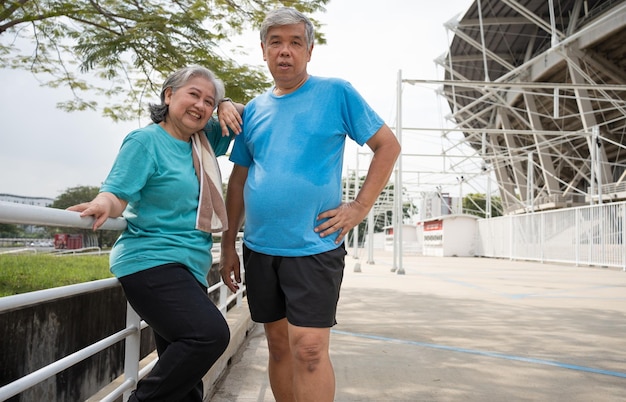 Photo des couples heureux et souriants, des personnes âgées asiatiques se tenant sur les escaliers pour se reposer après l'entraînement, faisant du jogging le matin, des seniors faisant de l'exercice en plein air pour une bonne santé.