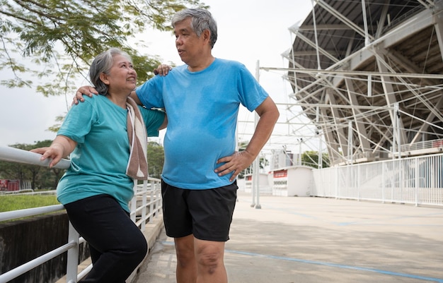 Photo des couples heureux et souriants, des personnes âgées asiatiques se tenant sur les escaliers pour se reposer après l'entraînement, faisant du jogging le matin, des seniors faisant de l'exercice en plein air pour une bonne santé.