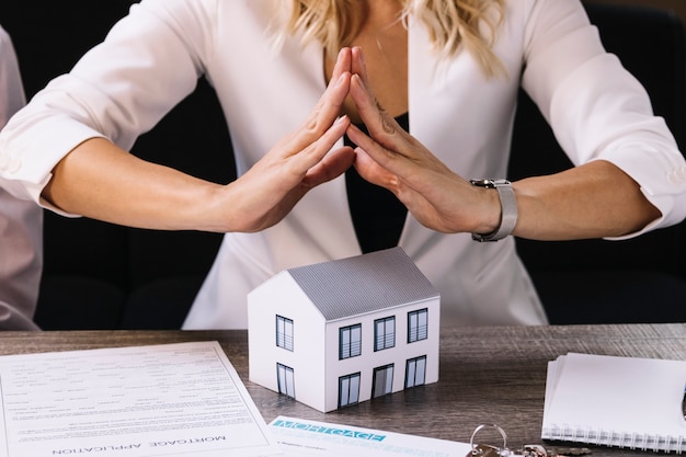 Crop femme tenant par la main au-dessus de la maison de jouet