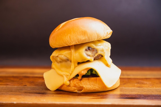 Photo délicieux burger à la saucisse de poulet double avec fromage mozzarella et salade sur planche de bois