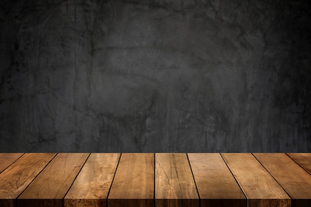 Dessus de table en bois avec fond flou de mur poli en béton foncé.