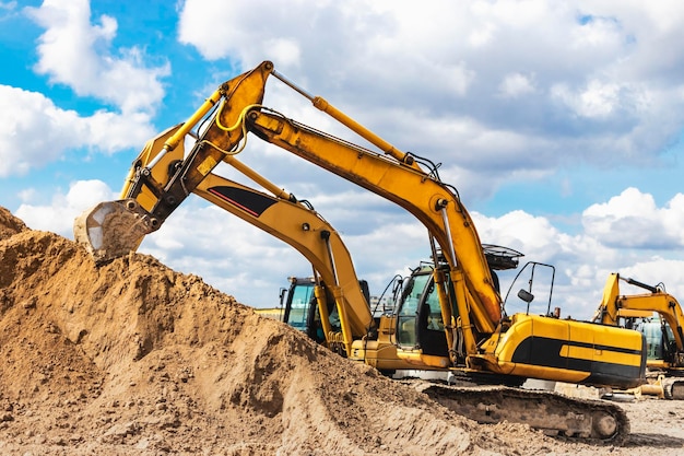 Deux excavatrices puissantes travaillent en même temps sur un chantier de construction ciel bleu ensoleillé en arrière-plan Matériel de construction pour les travaux de terrassement