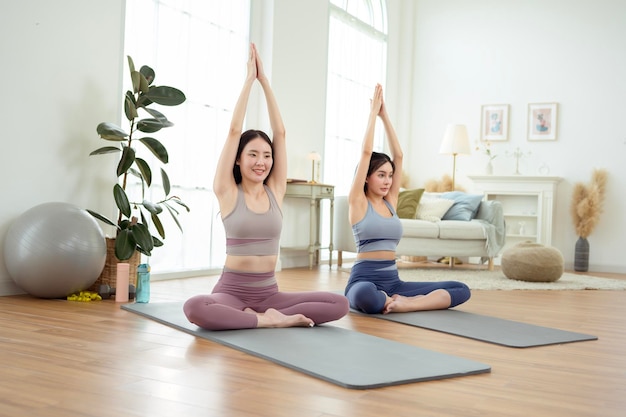 Photo deux jeunes amies asiatiques pratiquent le yoga à la maison.