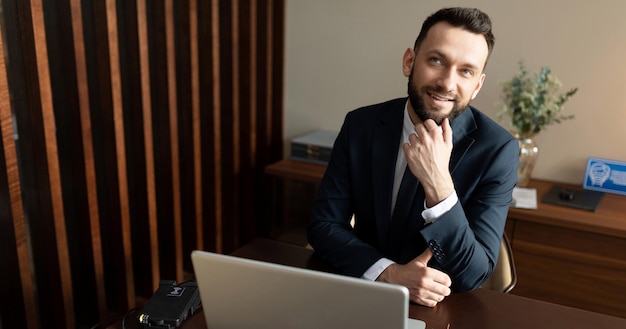 Directeur d'une compagnie d'assurance au bureau sur le lieu de travail avec un sourire en regardant la caméra