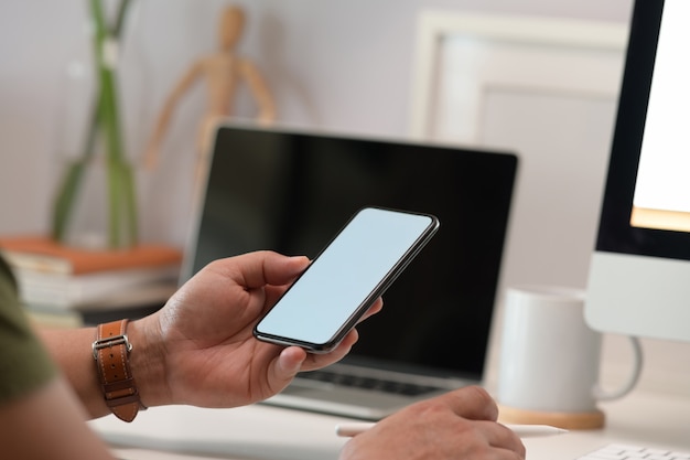 Écran blanc maquette téléphone portable dans la main de l&#39;homme à la maison