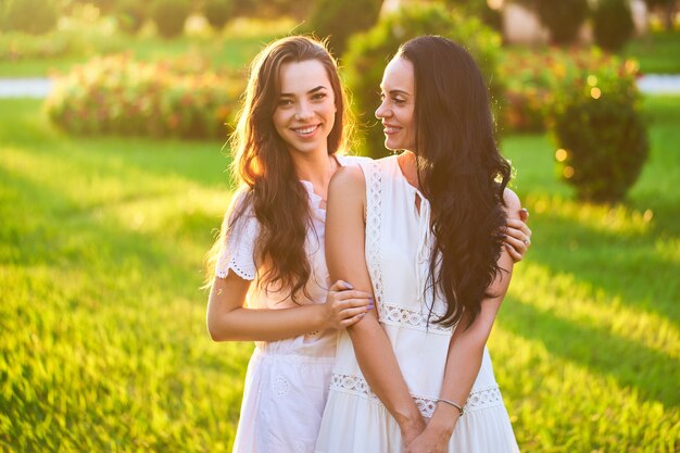 Élégante jolie mère heureuse souriante et fille joyeuse ensemble dans un parc en plein air au coucher du soleil à la lumière douce