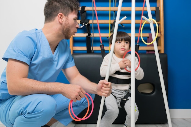 Enfant mignon atteint de paralysie cérébrale faisant une thérapie musculo-squelettique à l'hôpital tout en riant et en ayant...