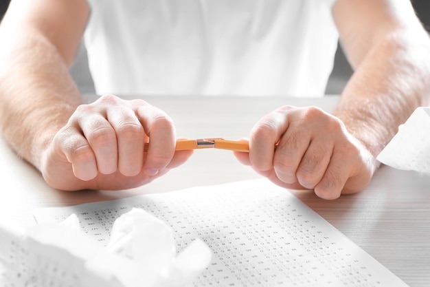 Photo Étudiant stressé cassant un crayon en passant un examen à table