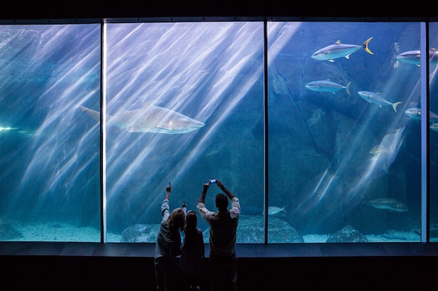 Photo famille heureuse en regardant le réservoir de poissons à l&#39;aquarium