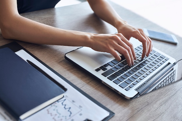 Femme d'affaires au bureau seule assise à table en tapant un message sur un ordinateur portable en gros plan de communication d'entreprise