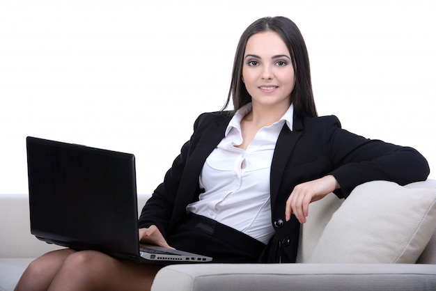 Femme d'affaires travaillant sur un ordinateur portable assis sur un canapé.