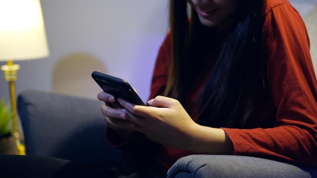 Une femme asiatique discute sur mobile à la maison. Détendez-vous et style de vie la nuit.