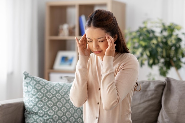 Photo une femme asiatique malade qui a mal à la tête à la maison