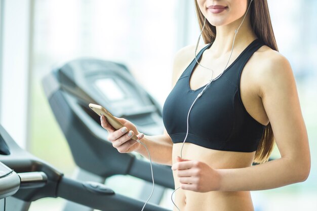 Photo la femme athlétique tient un téléphone dans le club de remise en forme