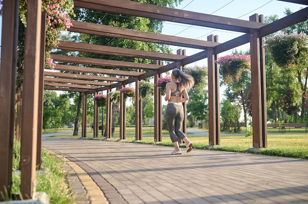 Photo une femme aux cheveux longs en tenue de sport jogging dans le parc