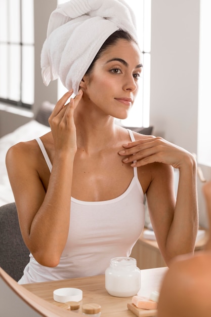 Femme ayant une journée de détente et à l'aide de crème pour le visage