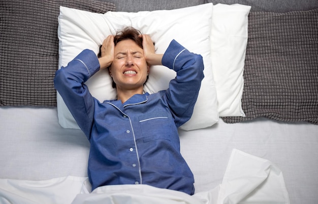 Femme caucasienne sans sommeil en pyjama touchant