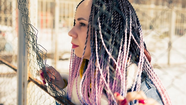 Photo femme élégante s'appuyant sur une clôture métallique jeune femme sérieuse dans des vêtements chauds regardant loin tout en s'appuyant sur une clôture nette sur la rue