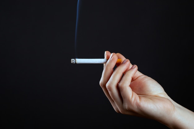 Femme main tenant une cigarette fumer de gros plan d'utilisation de la nicotine.