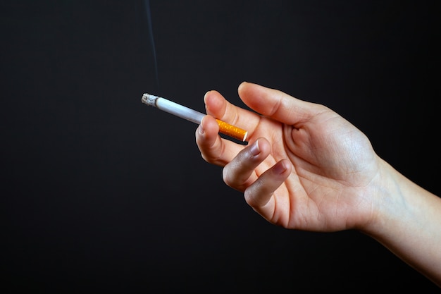 Femme main tenant une cigarette fumer de gros plan d'utilisation de la nicotine.