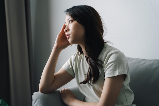 Une femme malheureuse, solitaire et déprimée est assise sur le canapé et tient sa tête.