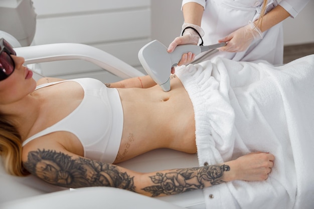 Femme recevant un traitement au laser abdominal dans un salon de beauté