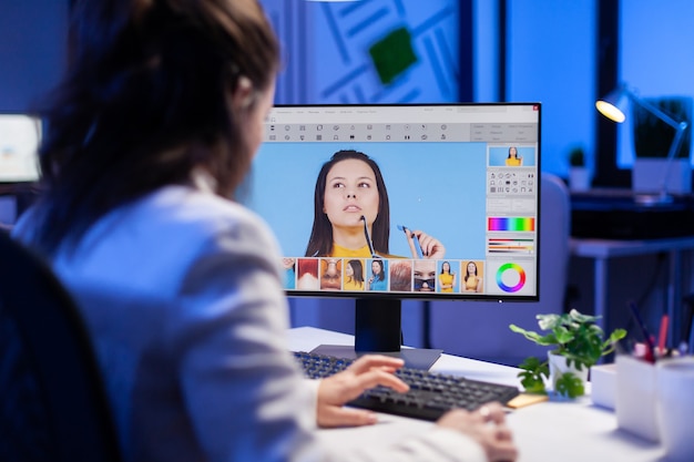 Femme retoucheuse indépendante travaillant des heures supplémentaires sur un ordinateur portable avec un logiciel de retouche photo