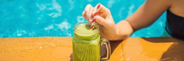 Photo femme avec un smoothie vert d'épinards et de banane sur le fond de la piscine des aliments sains