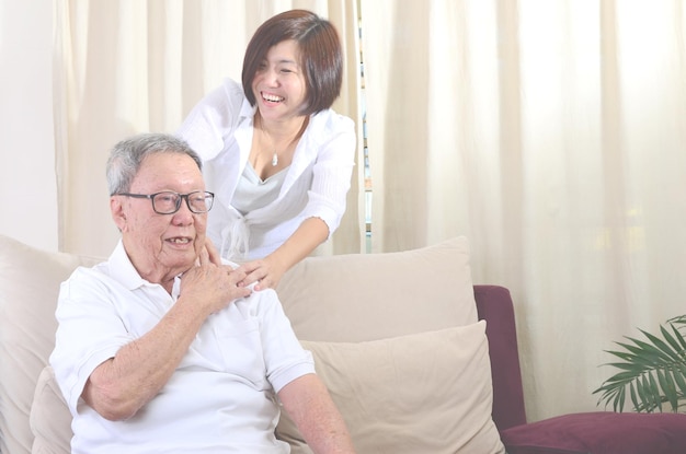 Photo une femme souriante donne un massage des épaules à son père à la maison.