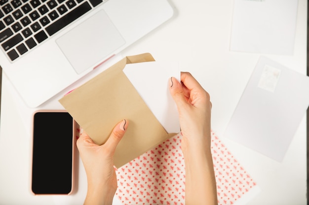 Photo fermez les mains d'une femme qui s'ouvre, reçoit une carte de voeux pour le nouvel an et noël 2021 d'amis ou de famille. lire une lettre avec mes meilleurs vœux, ouvrir une enveloppe. vacances, célébration.