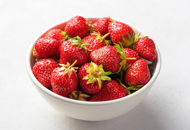 Fraises dans un bol blanc gros plan sur un fond clair