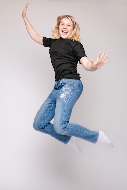 Photo gaie jeune femme brune dans des perspectives décontractées sautant dans les airs en studio.