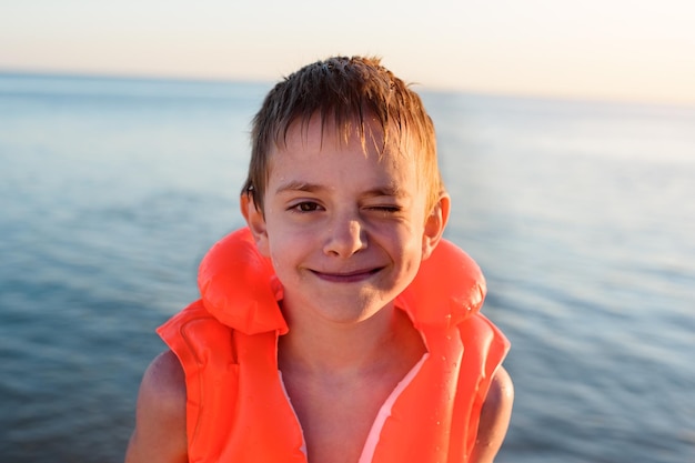 Garçon mignon avec un sourire heureux en natation gonflable contre la mer