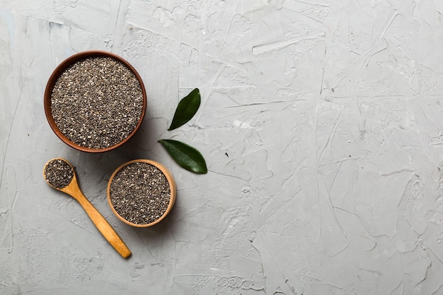 Graines de chia dans un bol et une cuillère sur fond coloré Salvia hispanica saine dans un petit bol Superfood sain