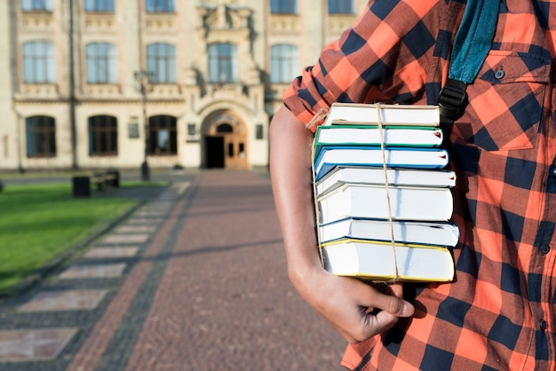 Gros plan d&#39;un adolescent tenant des livres sous son bras