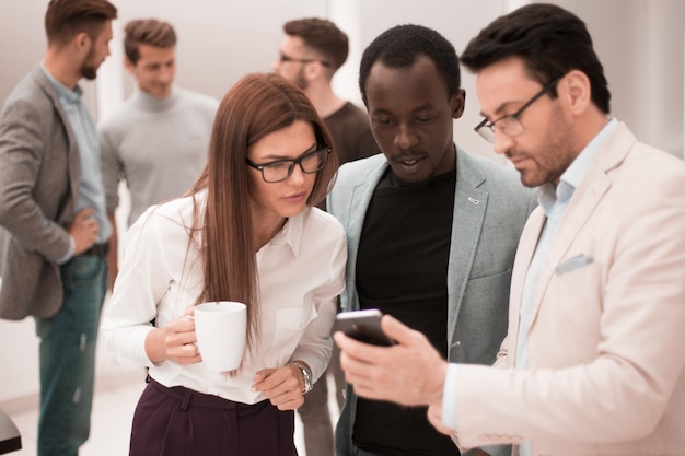 Gros plan sur un groupe d'employés lisant un message sur un smartphone