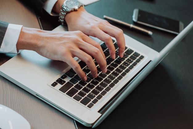 Gros plan de la main de l&#39;homme d&#39;affaires en tapant sur le clavier d&#39;ordinateur portable, le bruit et le grain.