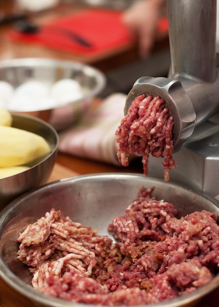 Gros plan de la partie avant du hachoir à viande ou de la machine à hacher avec de la viande hachée dans