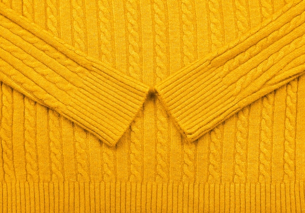 Photo gros plan sur la texture d'arrière-plan du pull en jersey de laine tricoté par câble jaune chaud avec motif de tresse en rangée