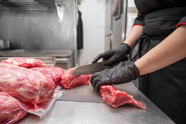 Gros plan sur de la viande crue et une femme boucher coupant de la viande avec un couteau