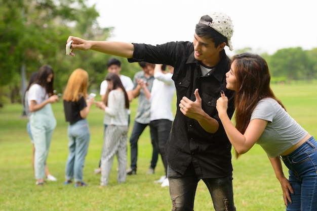 Groupe de jeunes amis asiatiques traîner et se détendre ensemble dans le parc en plein air