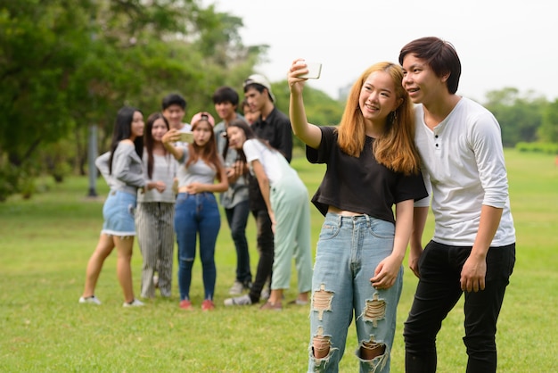 Groupe de jeunes amis asiatiques traîner et se détendre ensemble dans le parc en plein air