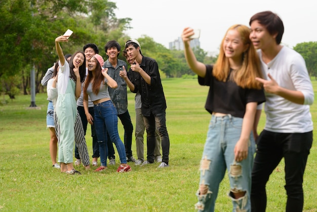 Groupe de jeunes amis asiatiques traîner et se détendre ensemble dans le parc en plein air