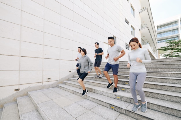 Groupe de jeunes asiatiques actifs faisant du jogging dans les escaliers à l'extérieur le matin